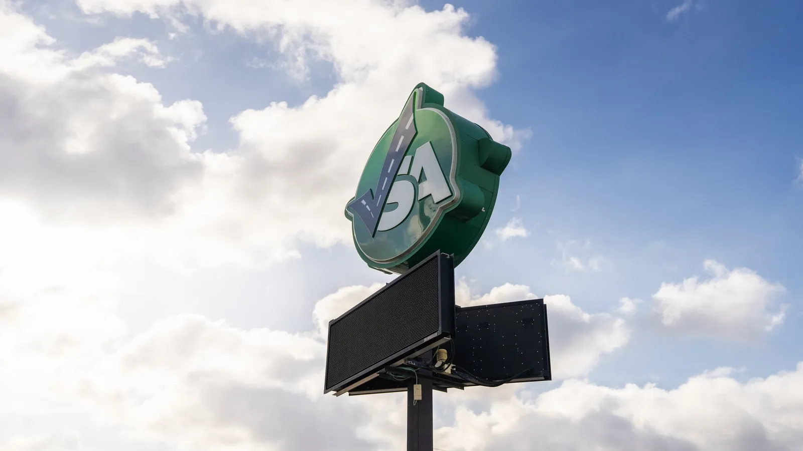 The Smart Auto pylon sign and its LED message board against a blue sky with scattered cloud